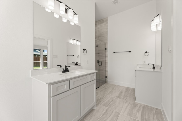 bathroom with a shower stall, two vanities, a sink, and baseboards