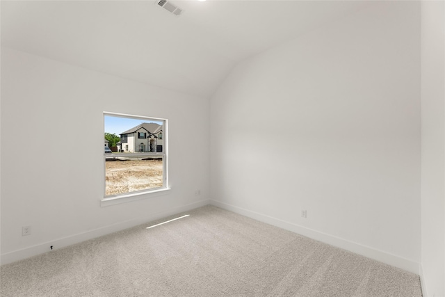 carpeted spare room featuring baseboards, lofted ceiling, and visible vents
