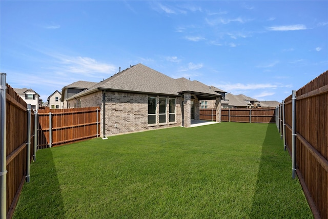 back of property featuring roof with shingles, a yard, a fenced backyard, and brick siding