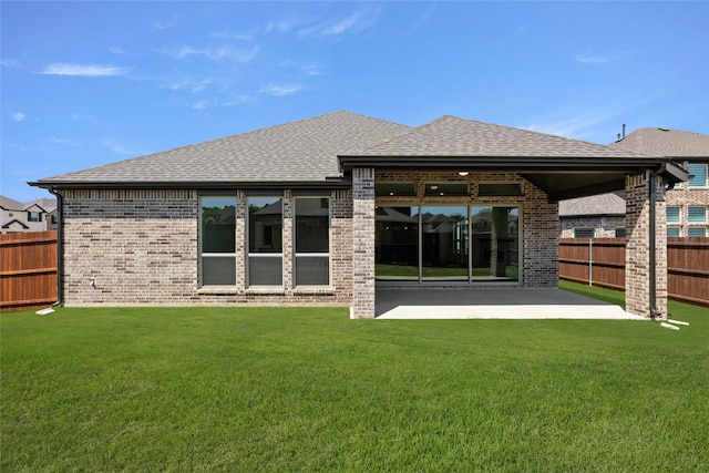 rear view of property featuring brick siding, fence, a patio, and roof with shingles