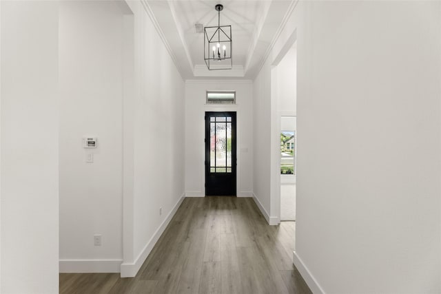 doorway with a chandelier, baseboards, crown molding, and wood finished floors