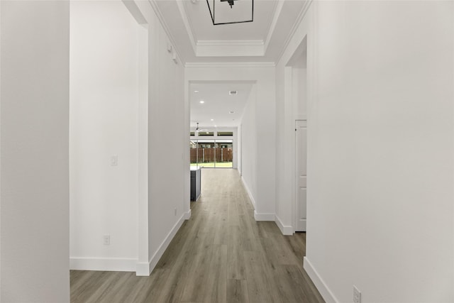 hall with light wood-style flooring, crown molding, and baseboards