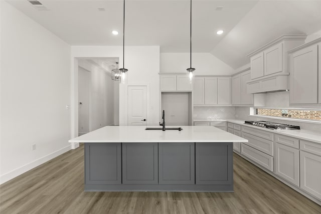 kitchen featuring backsplash, a kitchen island with sink, visible vents, stainless steel gas stovetop, and a sink