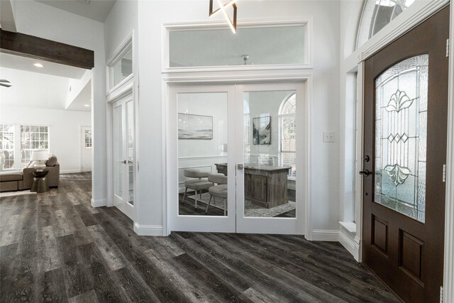 foyer with french doors, dark wood-style floors, baseboards, healthy amount of natural light, and a towering ceiling