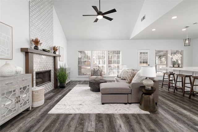 living area with high vaulted ceiling, a ceiling fan, dark wood finished floors, a tile fireplace, and recessed lighting