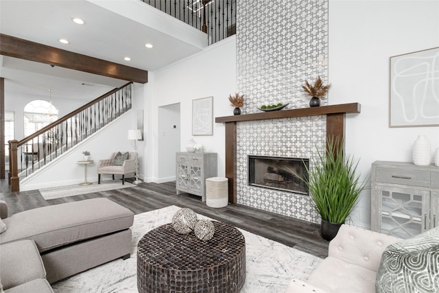 living room featuring a towering ceiling, a fireplace, hardwood / wood-style floors, and beam ceiling