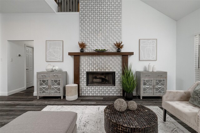 living area featuring wood finished floors, high vaulted ceiling, baseboards, and a fireplace