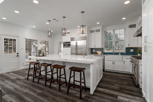 kitchen with built in appliances, a sink, dark wood finished floors, recessed lighting, and white cabinets