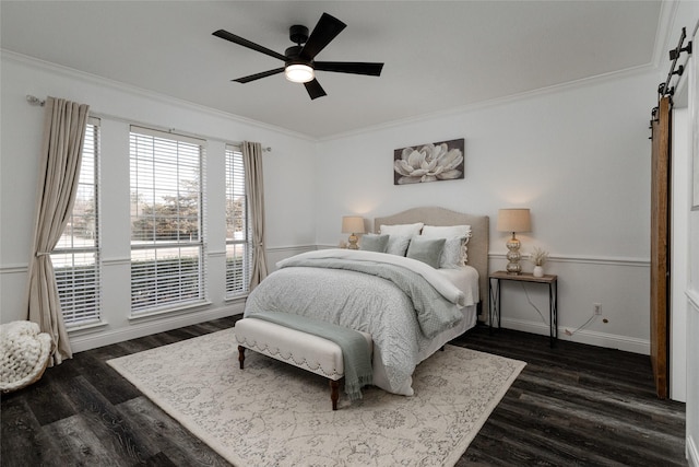 bedroom featuring a barn door, crown molding, dark wood finished floors, baseboards, and a ceiling fan