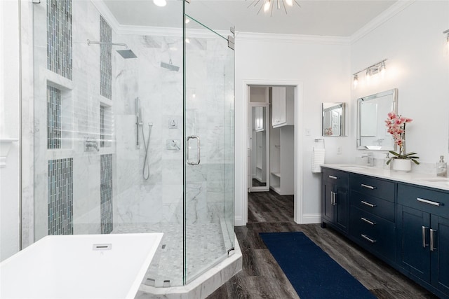 bathroom featuring hardwood / wood-style flooring, ornamental molding, separate shower and tub, and vanity