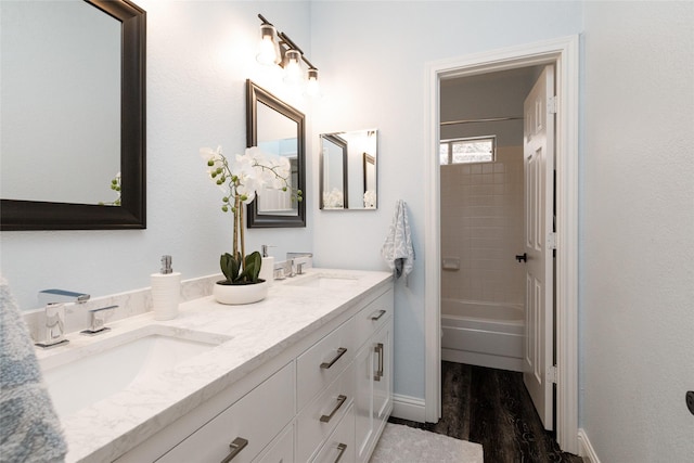 bathroom with hardwood / wood-style flooring, vanity, and tiled shower / bath combo