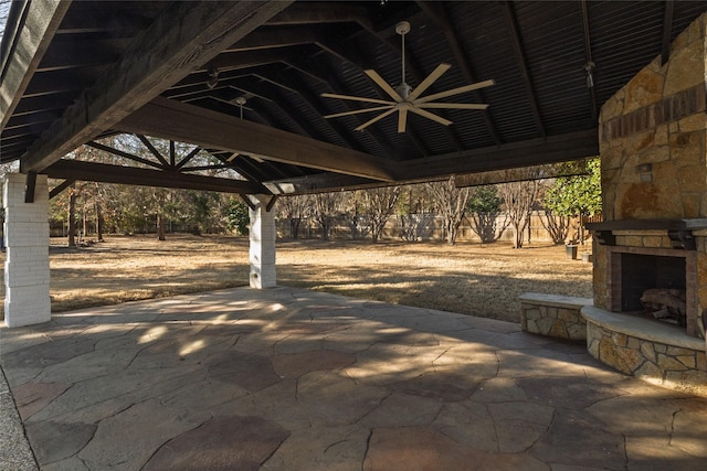 view of patio featuring an outdoor stone fireplace, a gazebo, and ceiling fan