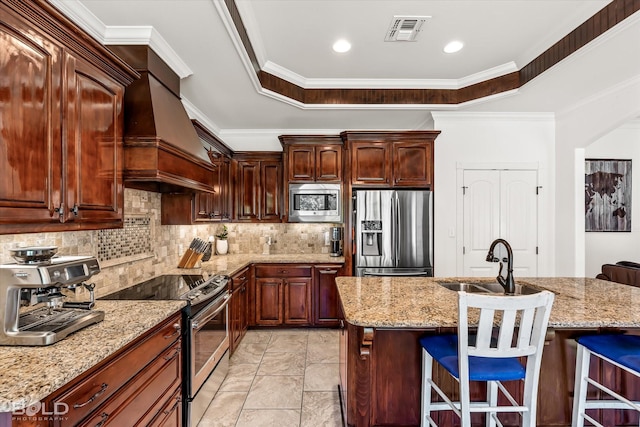 kitchen with appliances with stainless steel finishes, sink, a breakfast bar area, light stone counters, and a center island with sink