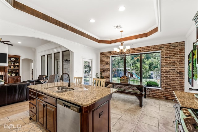 kitchen with brick wall, decorative light fixtures, dishwasher, sink, and a kitchen island with sink