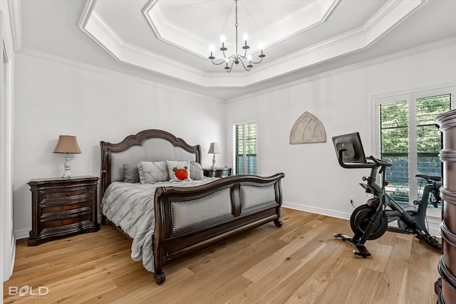 bedroom featuring a chandelier, a raised ceiling, multiple windows, and light hardwood / wood-style flooring