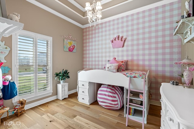 bedroom with crown molding, a chandelier, light hardwood / wood-style floors, and a tray ceiling