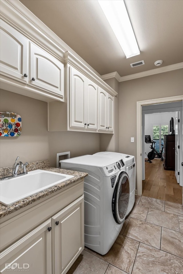 washroom with cabinets, washing machine and dryer, sink, and crown molding