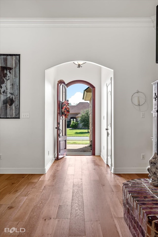 foyer entrance with crown molding and light wood-type flooring