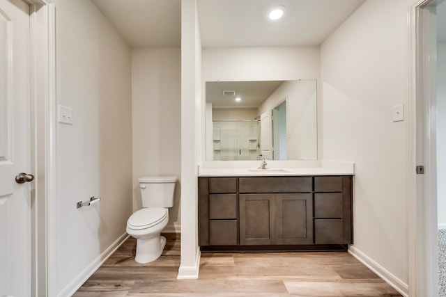 bathroom featuring hardwood / wood-style flooring, vanity, walk in shower, and toilet