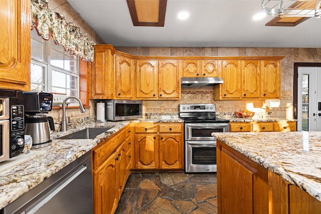 kitchen with light stone counters, sink, backsplash, and appliances with stainless steel finishes