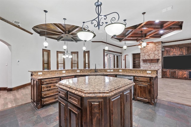 kitchen with arched walkways, stone tile floors, hanging light fixtures, a kitchen island, and coffered ceiling