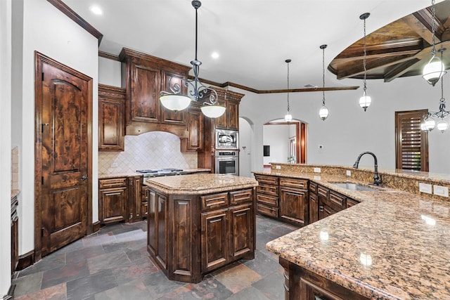 kitchen with arched walkways, pendant lighting, a large island, stainless steel appliances, and a sink