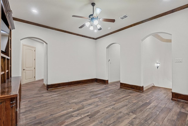 spare room featuring arched walkways, dark wood-style flooring, a ceiling fan, visible vents, and baseboards