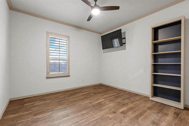 unfurnished room featuring built in features, crown molding, a ceiling fan, wood finished floors, and baseboards