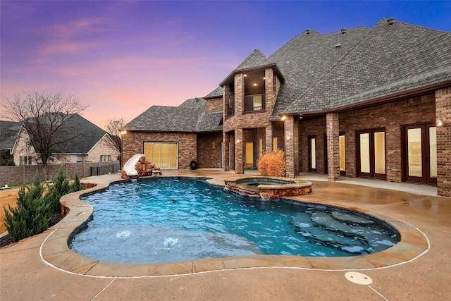 view of swimming pool with a pool with connected hot tub, a water slide, fence, and a patio