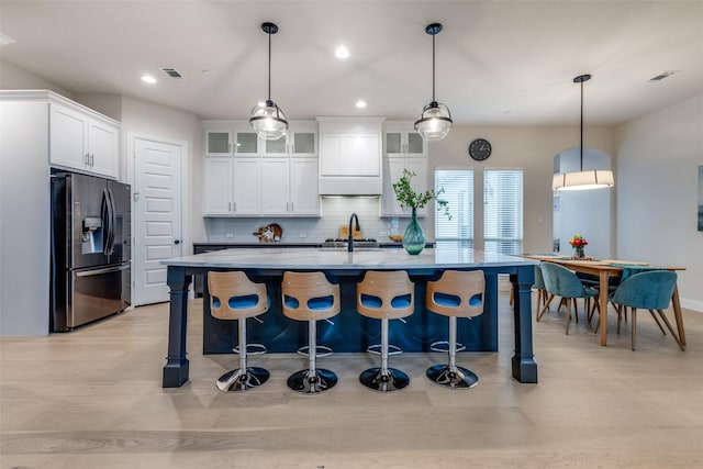 kitchen with hanging light fixtures, white cabinets, and stainless steel refrigerator with ice dispenser