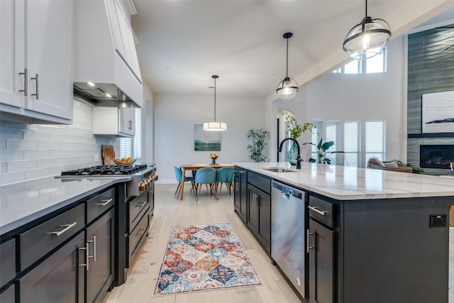 kitchen featuring appliances with stainless steel finishes, pendant lighting, white cabinetry, an island with sink, and sink