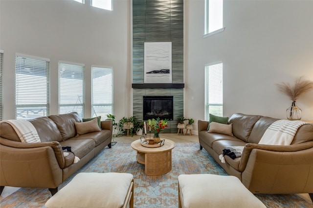 living room with a towering ceiling, a fireplace, and wood-type flooring