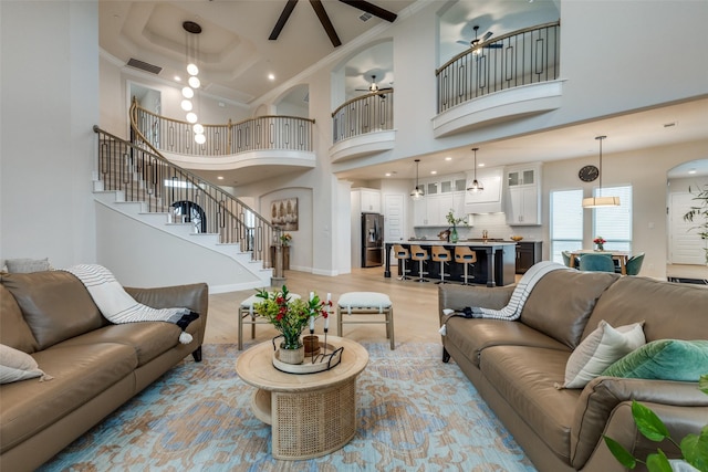 living room with ceiling fan, ornamental molding, light hardwood / wood-style flooring, and a high ceiling