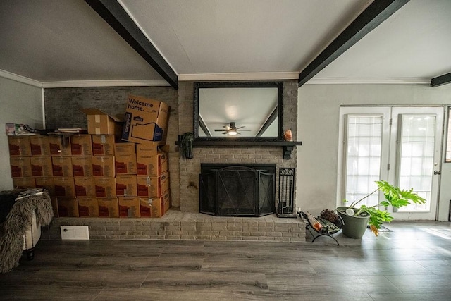 living room with crown molding, beam ceiling, a fireplace, and wood-type flooring