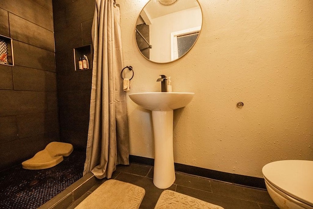 bathroom featuring walk in shower, tile patterned floors, and toilet