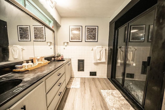 bathroom with walk in shower, wood-type flooring, tile walls, and vanity