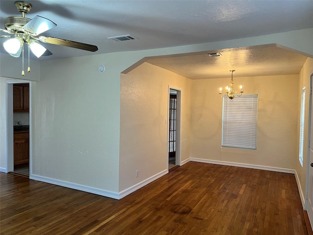 empty room featuring dark hardwood / wood-style floors, ceiling fan with notable chandelier, and a textured ceiling