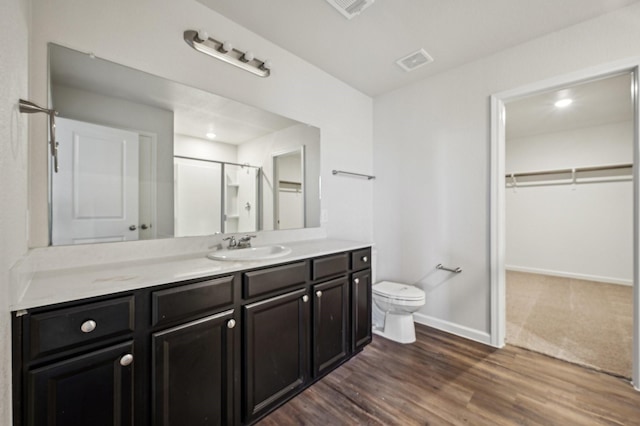 bathroom with vanity, toilet, hardwood / wood-style floors, and walk in shower