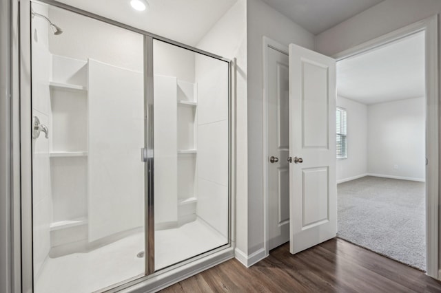 bathroom with wood-type flooring and an enclosed shower