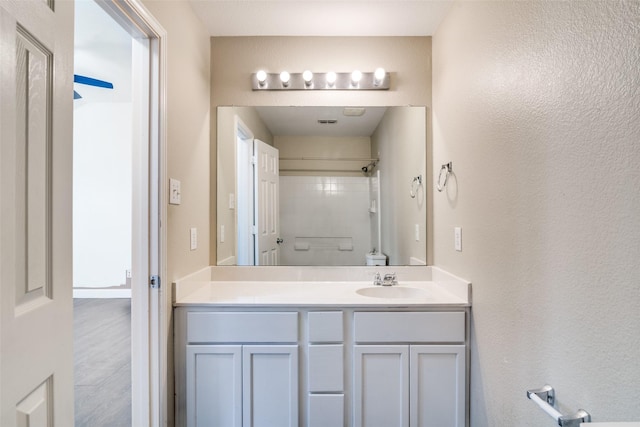 bathroom with vanity, toilet, and a shower