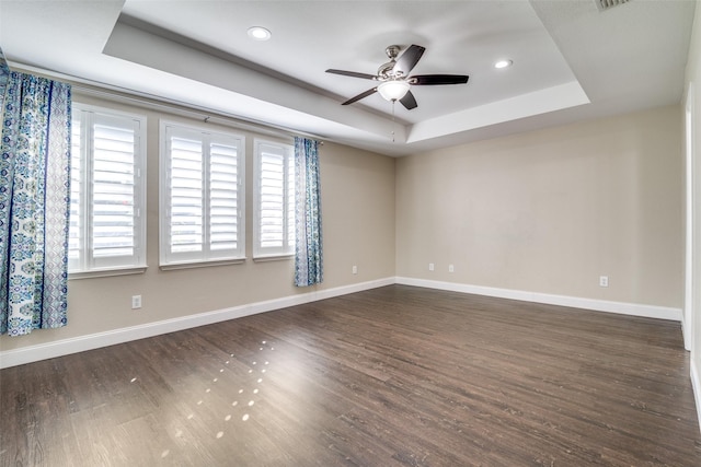 unfurnished room with a raised ceiling, dark hardwood / wood-style floors, and ceiling fan