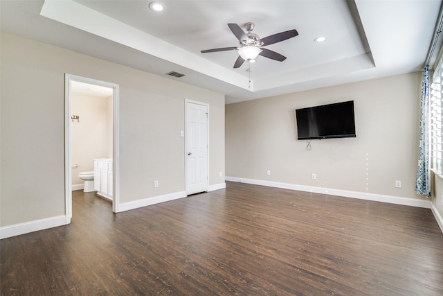 unfurnished living room featuring dark hardwood / wood-style flooring, a tray ceiling, and ceiling fan