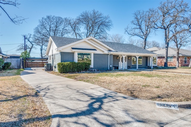 view of front of house with brick siding, central air condition unit, a porch, a front yard, and fence