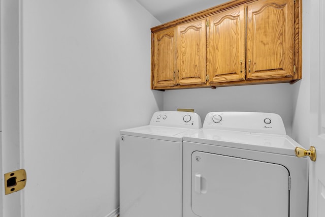 clothes washing area with cabinets and washer and dryer