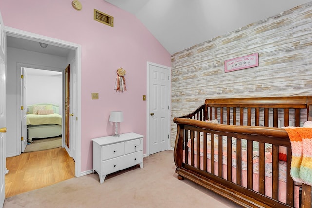 carpeted bedroom featuring a crib and vaulted ceiling