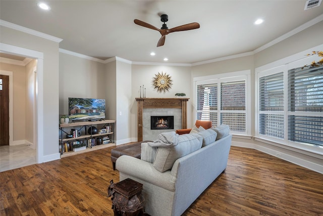 living room featuring a premium fireplace, dark wood-type flooring, ceiling fan, and crown molding