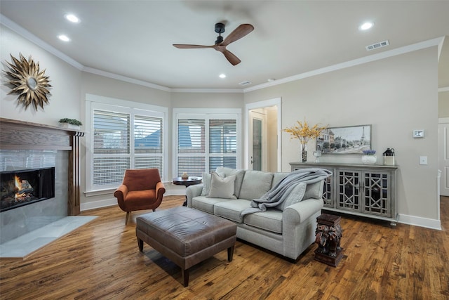 living room featuring a premium fireplace, dark wood-type flooring, ceiling fan, and crown molding