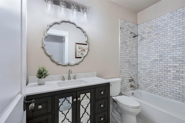 full bathroom featuring tiled shower / bath, vanity, and toilet