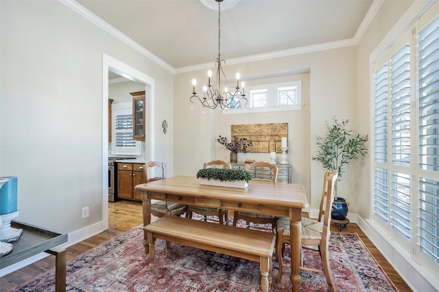 dining space with crown molding, light hardwood / wood-style flooring, and a notable chandelier