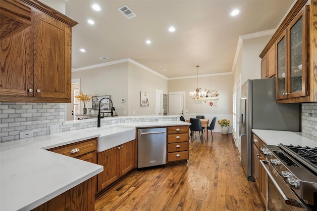 kitchen with sink, hanging light fixtures, kitchen peninsula, hardwood / wood-style flooring, and stainless steel appliances